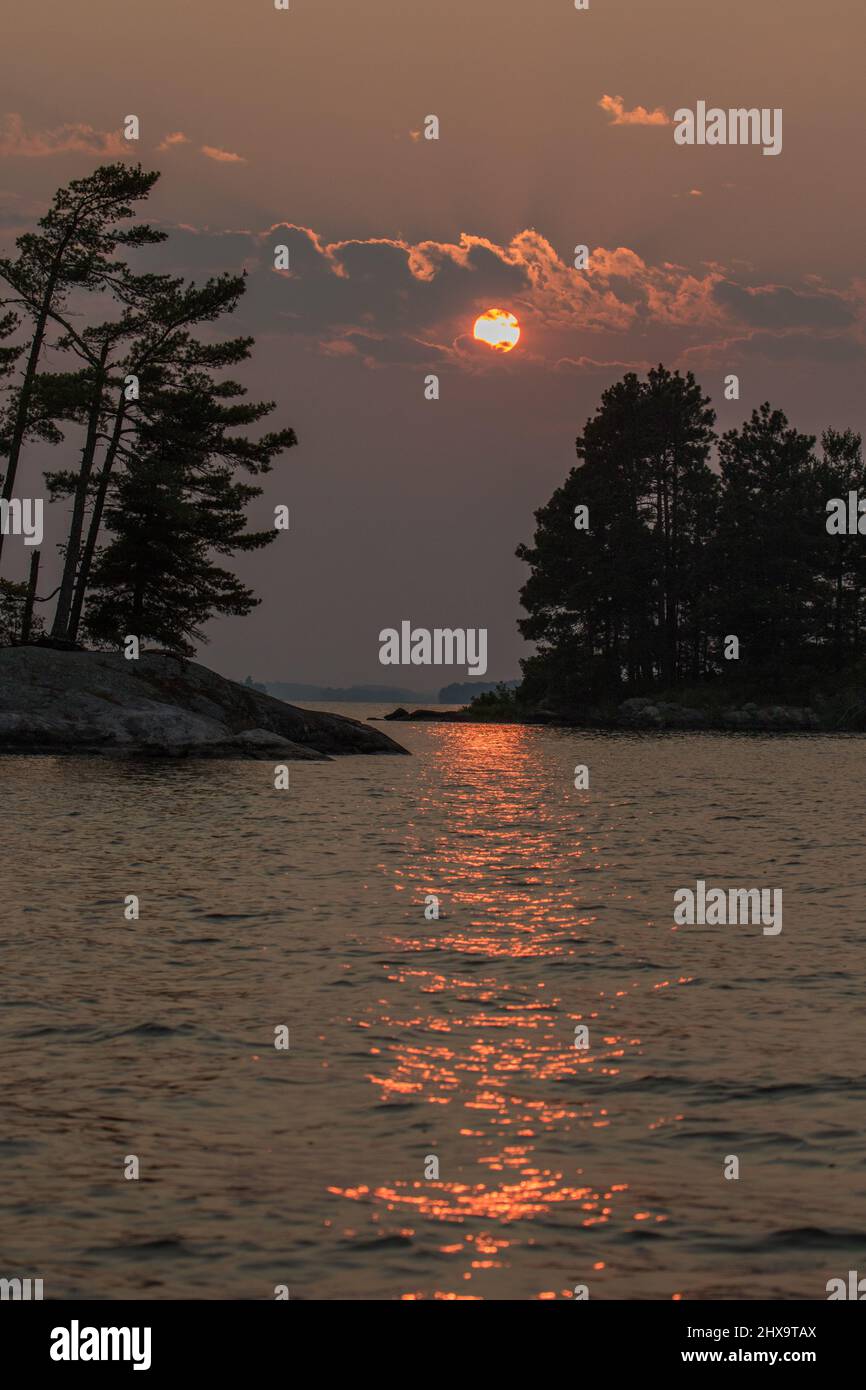 Il sole che tramonta sulle acque calme del lago Kabetogama, Voyageurs National Park, MN, USA Foto Stock