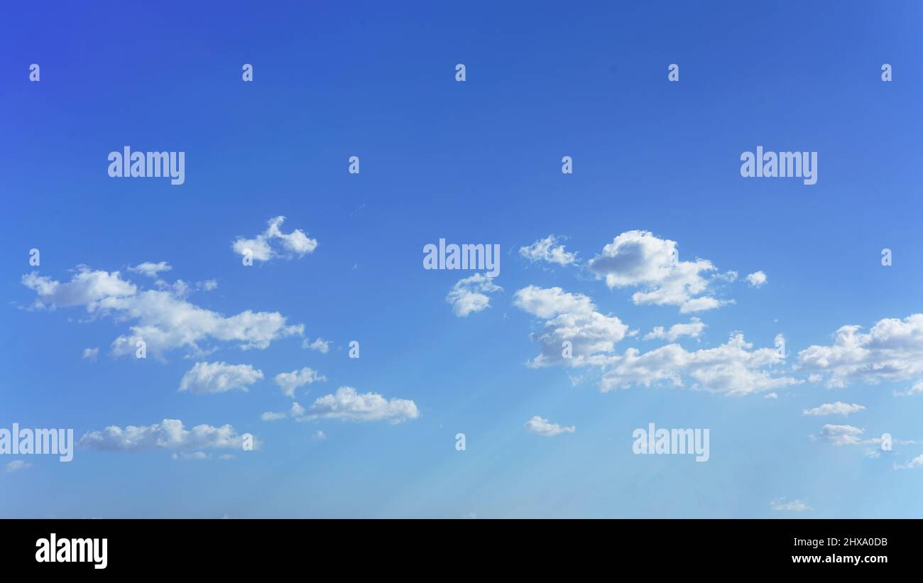 Nuvole bianche e soffici fino all'orizzonte con savana blu e deboli raggi del sole. Foto Stock