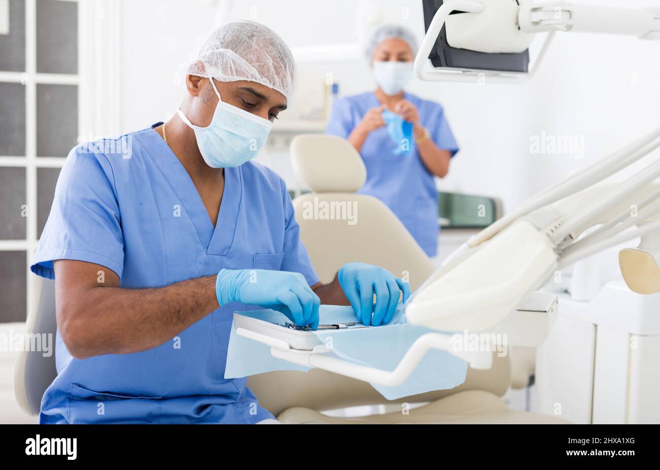 Controllo dentista mirato e disposizione degli strumenti in ufficio dentale Foto Stock