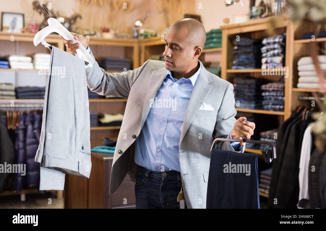 Uomo che sceglie giacca tuta in negozio di abbigliamento Foto Stock