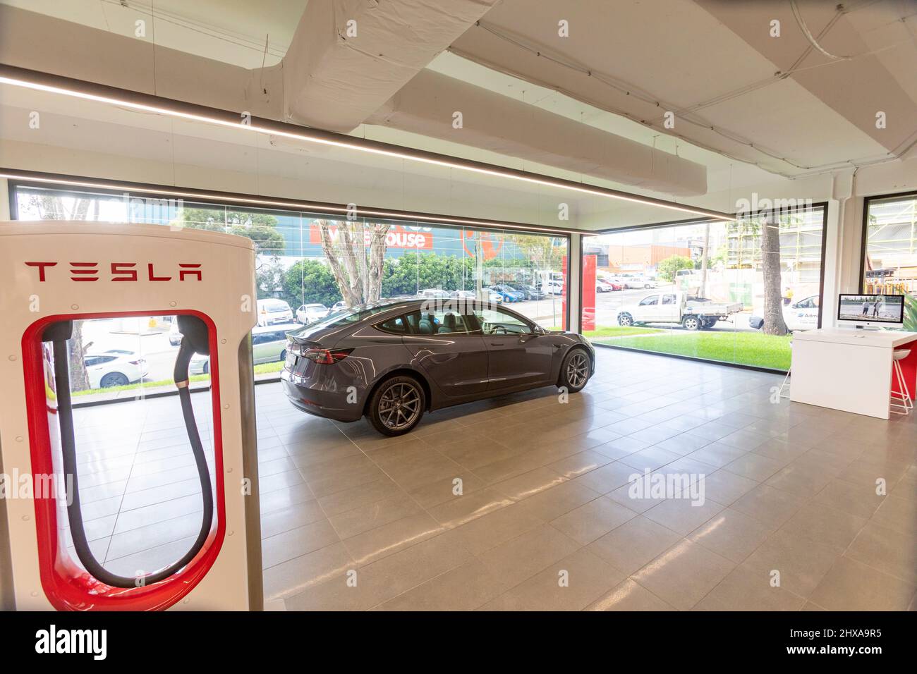 Showroom di Tesla car a Sydney con 2022 Tesla modello 3 in argento metallizzato in esposizione accanto al caricabatterie tesla, Sydney, Australia Foto Stock