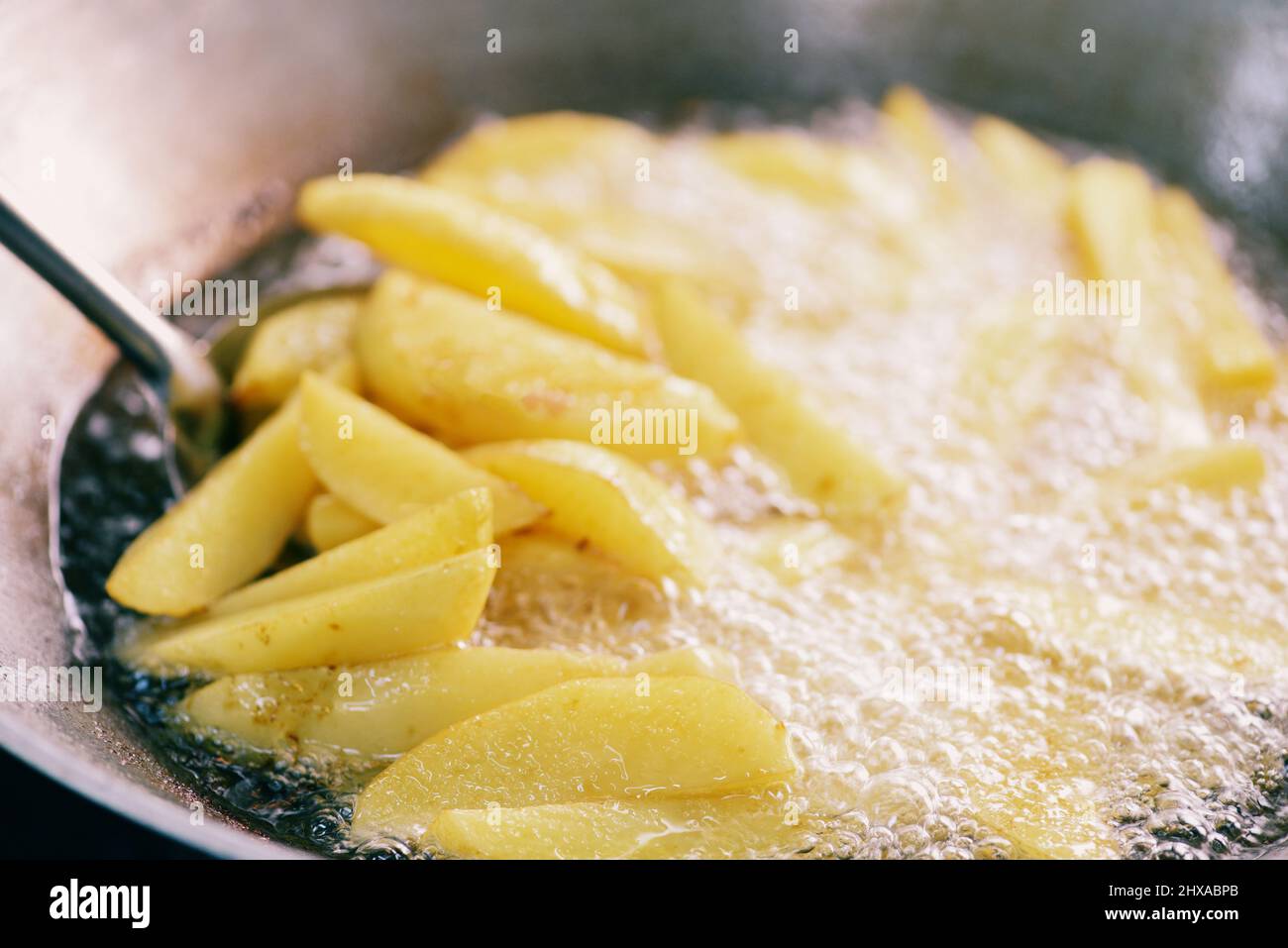 Cottura delle patatine fritte o friggere le patate in olio caldo per i  spicchi di patate, chiudere le patate fritte in olio sulla padella Foto  stock - Alamy