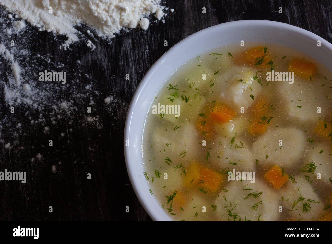 Vista superiore della zuppa nella ciotola con gnocchi su sfondo nero Foto Stock