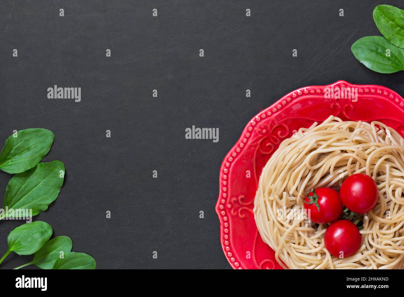 Vista dall'alto spaghetti di grano duro su piatto rosso su sfondo nero Foto Stock