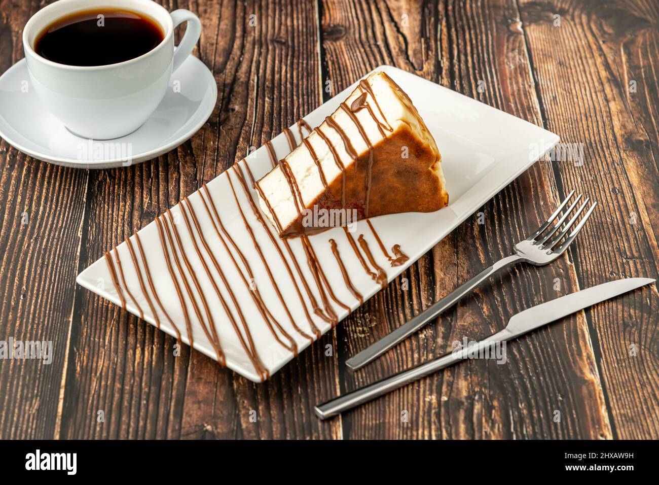 Cheesecake a fette di san sebastian con caffè su tavola di legno Foto Stock