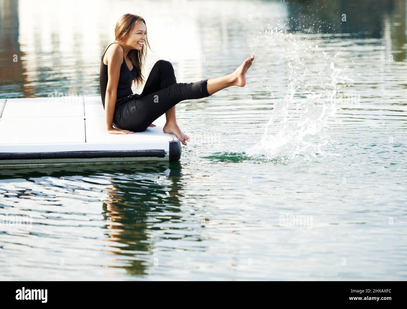 Reminiscing circa i suoi anni di infanzia. Una giovane donna meravigliosa che si è giocosamente baciata d'acqua al porto. Foto Stock