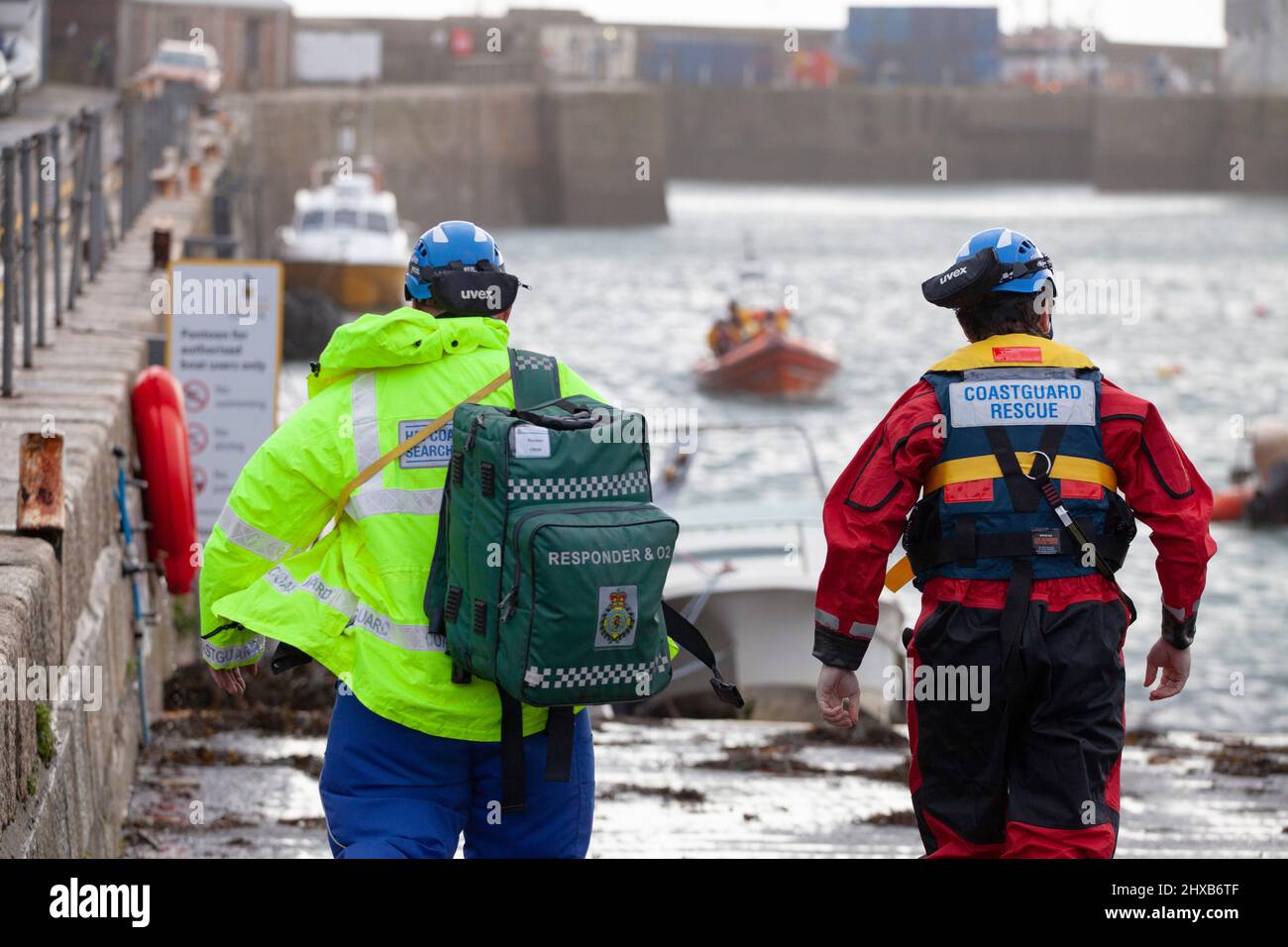 I soccorritori incontrano la scialuppa di salvataggio costiera per controllare una vittima estratta dall'acqua durante una tempesta in Cornovaglia. RNLIR di pronto soccorso Foto Stock