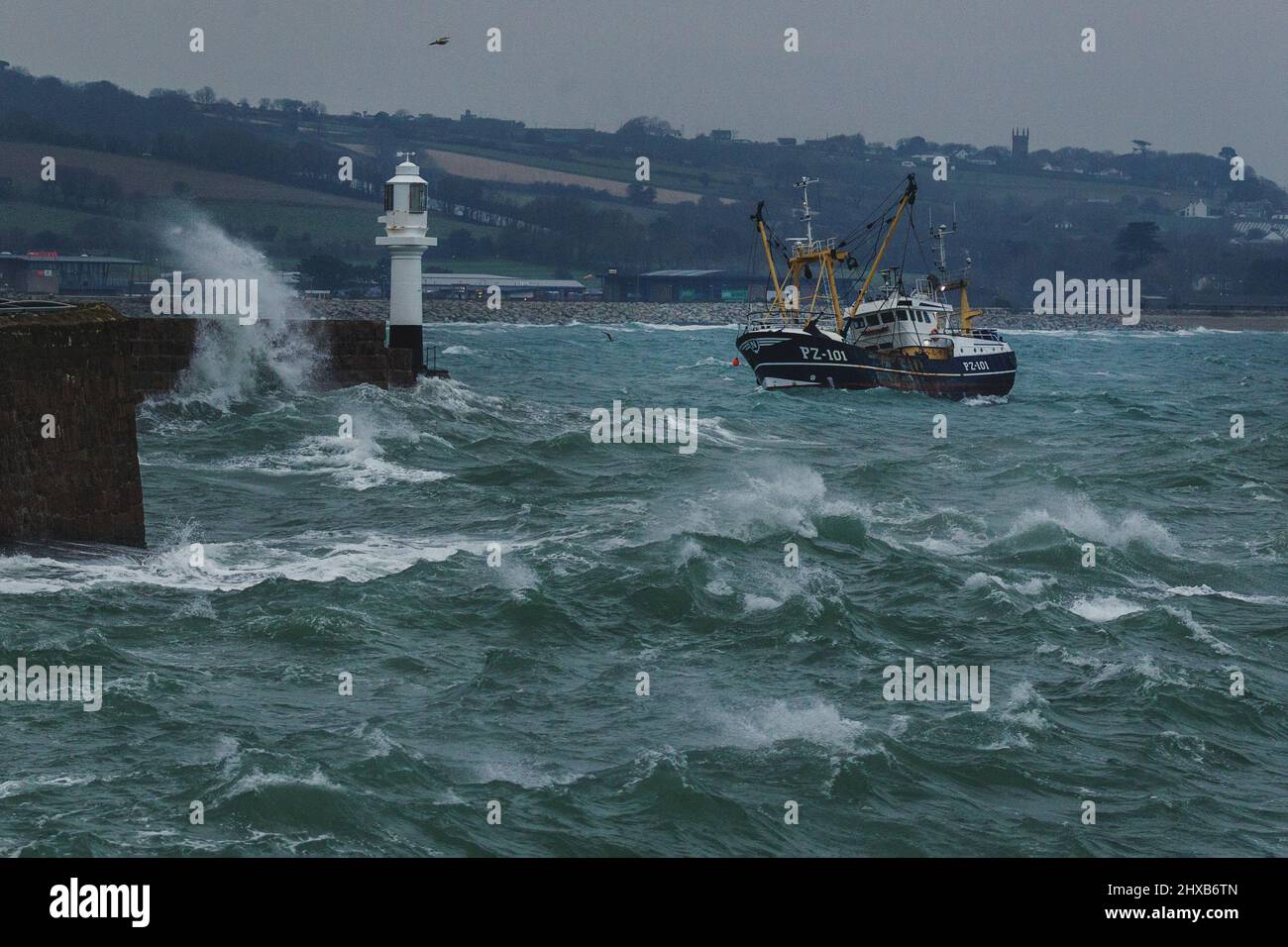 Un peschereccio a strascico proveniente dalla flotta di pescatori di Newlyn si sbatte selvaggiamente nei mari accidentati, mentre entra nel porto di Penzance per le riparazioni. Foto Stock