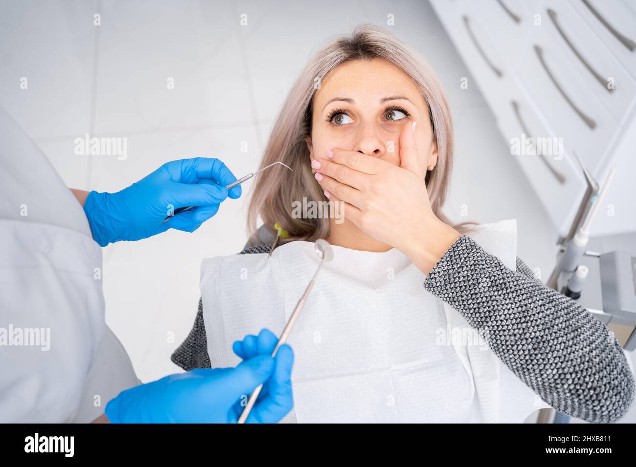 Il concetto di medicina e salute dentale, odontoiatria moderna, trattamento carie in clinica, una donna seduta in una sedia dentale, paura di un dentista Foto Stock
