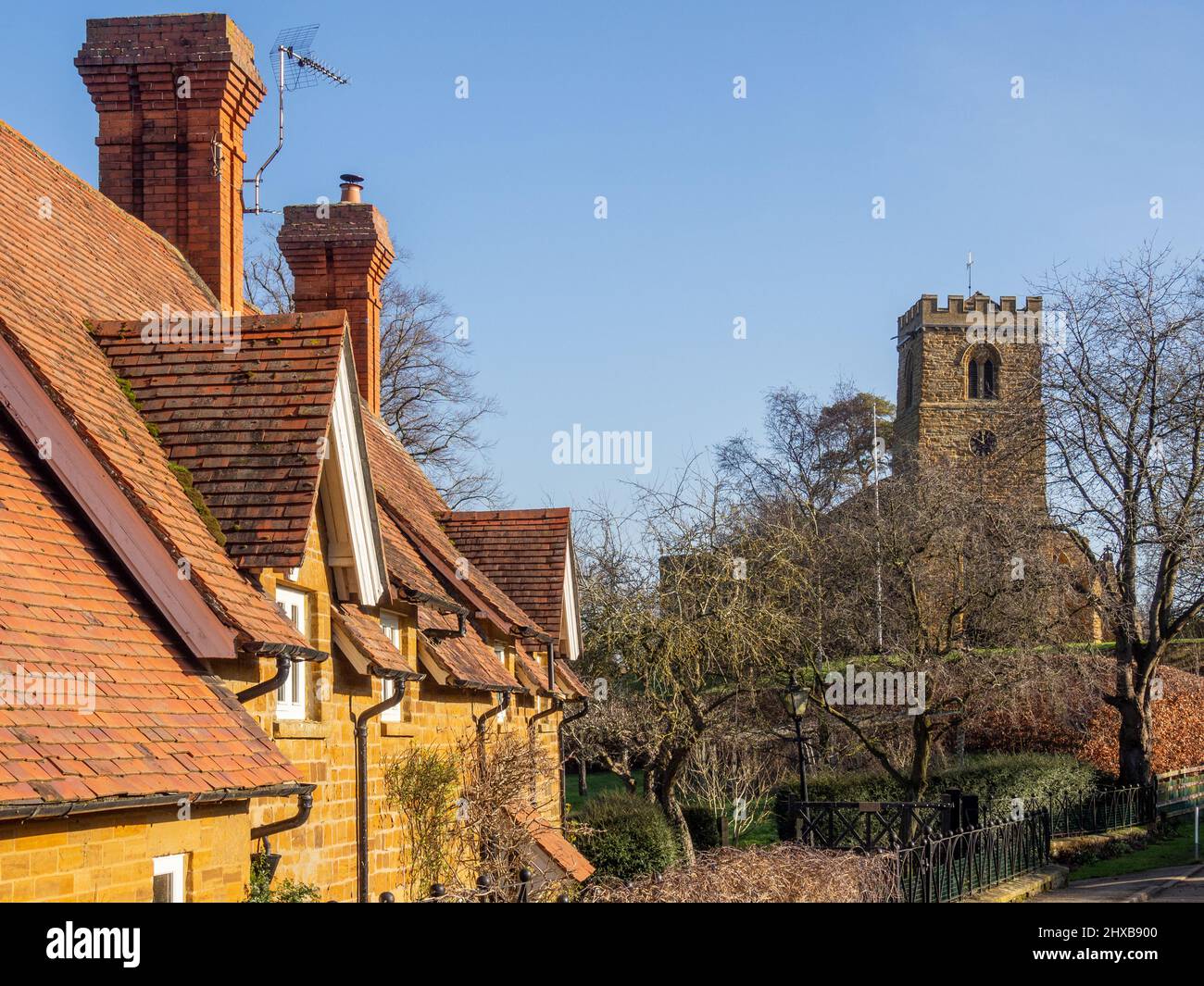 Scena stradale in inverno nel grazioso villaggio di Great Brington, Northamptonshire, Regno Unito; chiesa di St Mary sullo sfondo. Foto Stock