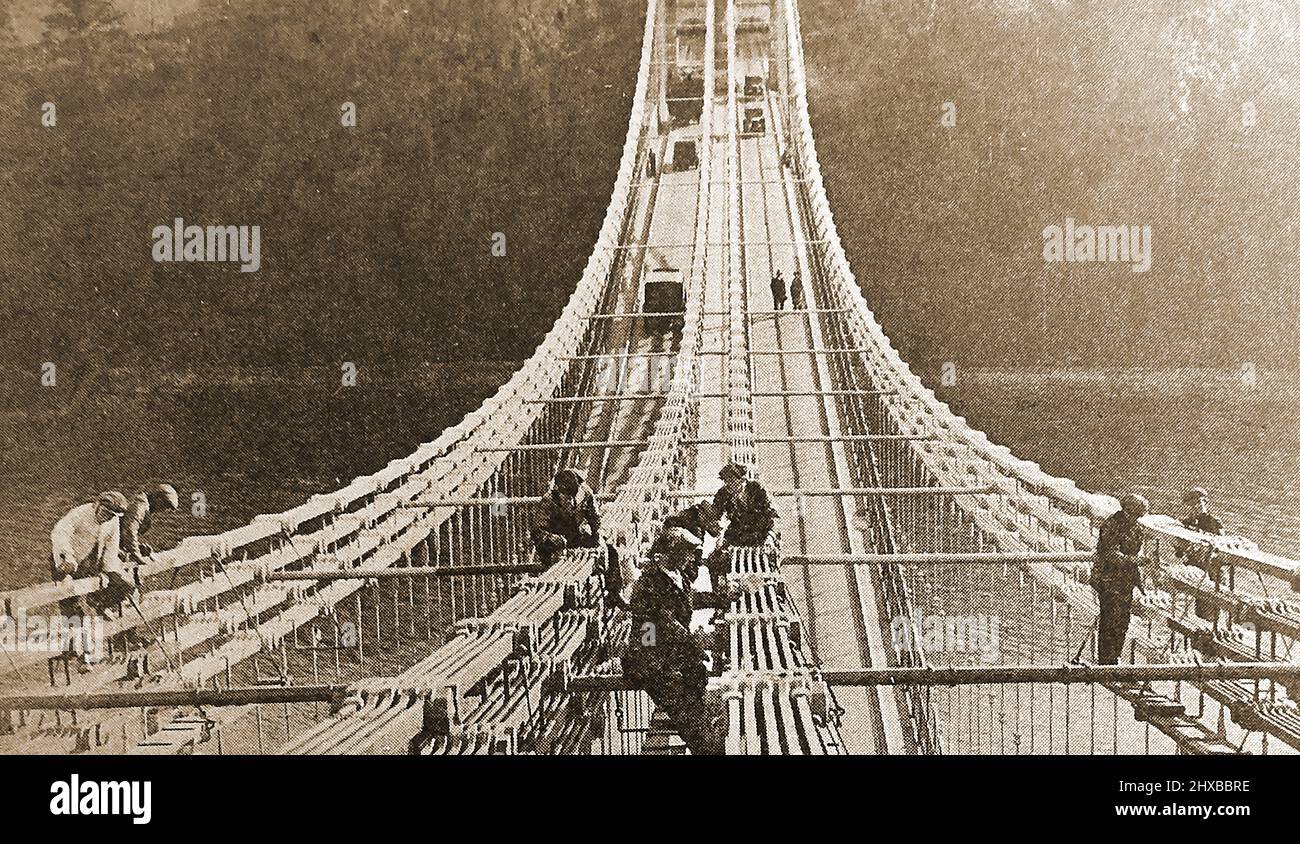 Un'immagine iniziale che mostra i lavoratori che dipingano il ponte sospeso Menai, Anglesey, Galles, Regno Unito senza alcun equipaggiamento di sicurezza. Foto Stock