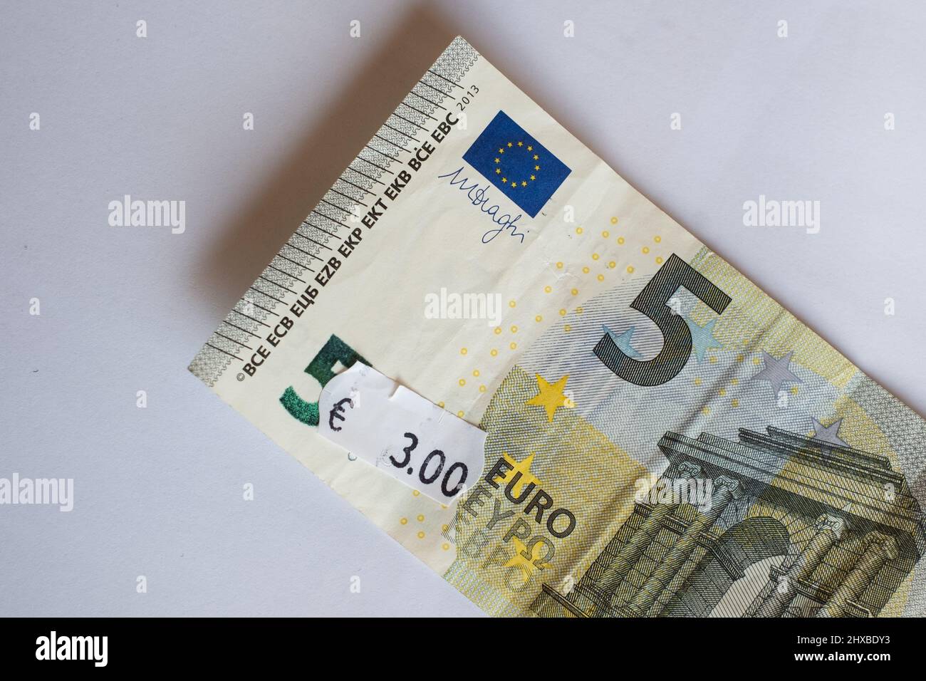 Banconota da cinque euro con prezzo di tre euro. Focalizzazione selettiva sull'etichetta. Inflazione in Europa, iperinflazione, concetto di svalutazione. Foto Stock