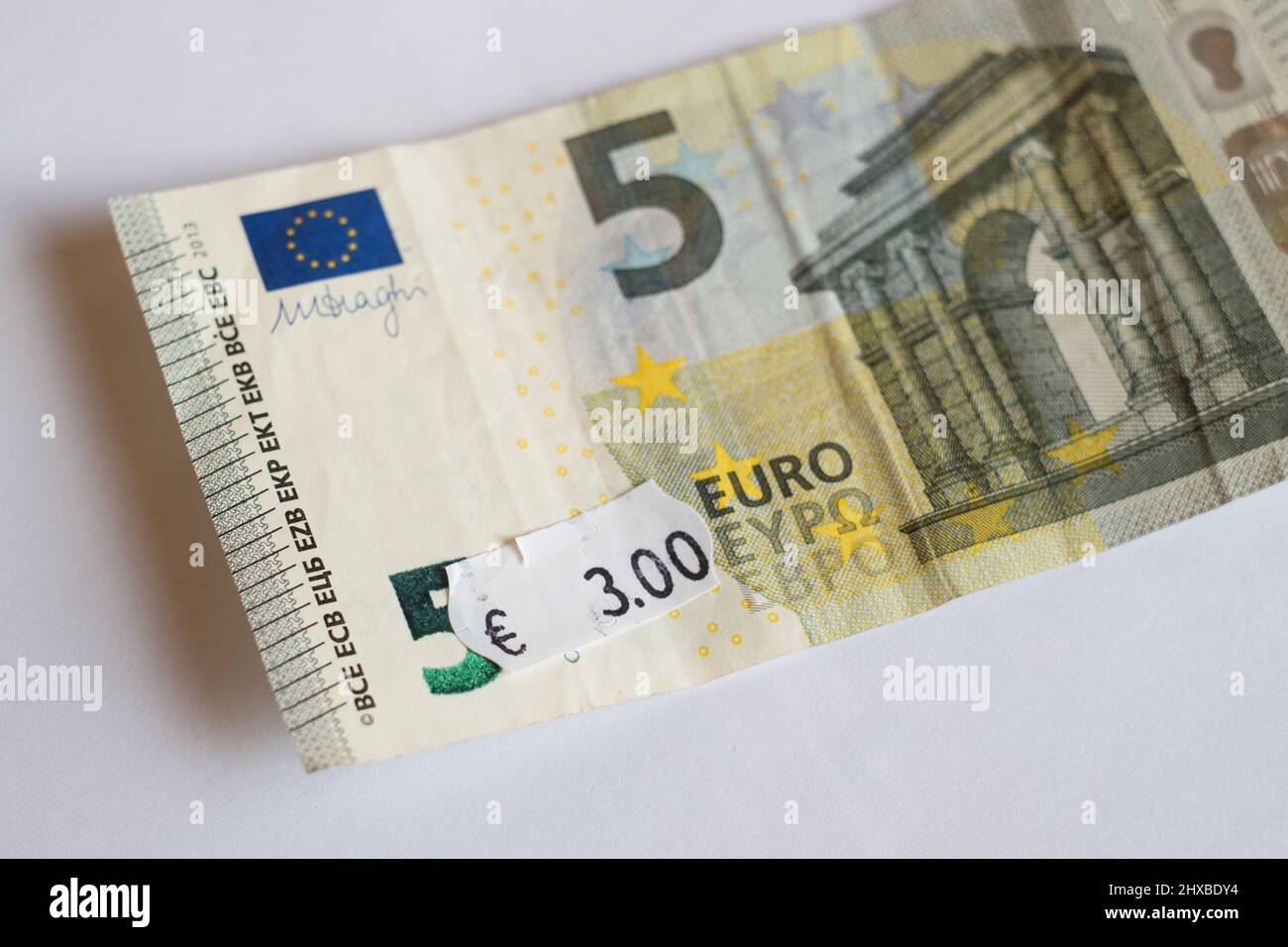 Banconota da cinque euro con prezzo di tre euro. Focalizzazione selettiva sull'etichetta. Inflazione in Europa, iperinflazione, concetto di svalutazione. Foto Stock