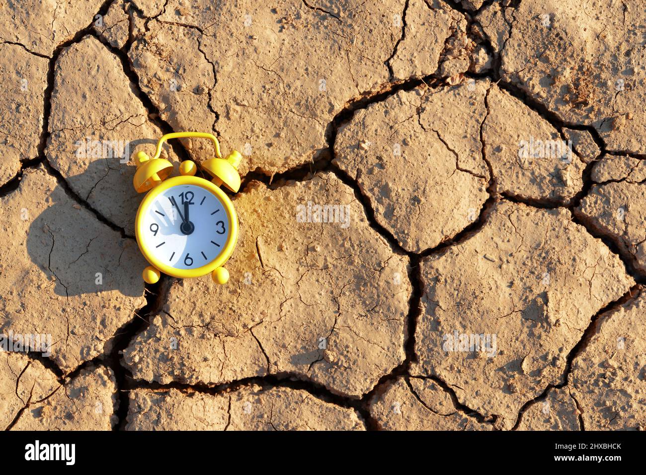 Sveglia con cinque minuti prima delle dodici su terreno arido cracked. Concetto di cambiamento climatico o riscaldamento globale. Foto Stock