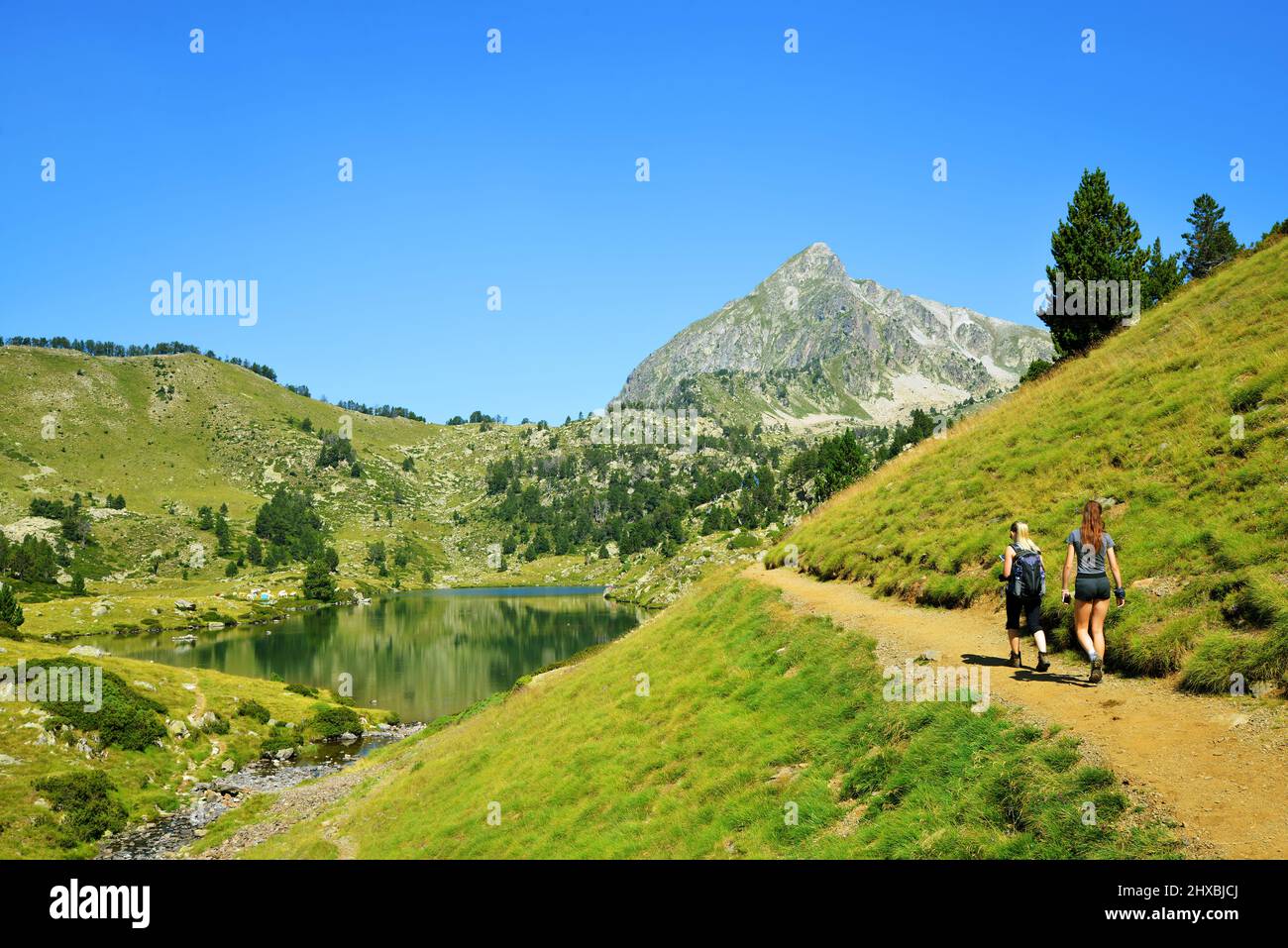 Escursionisti in un viaggio nella riserva naturale nazionale di Neouvielle, Lac du Milieu, Pirenei francesi. Bel paesaggio estivo di montagna in giornata di sole. Foto Stock