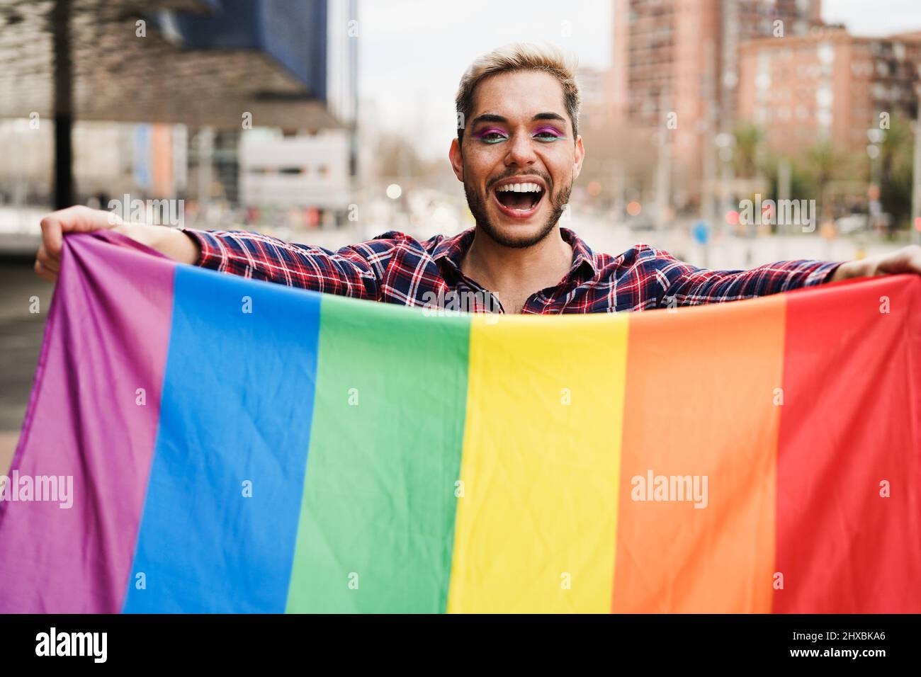 Gay uomo che ha divertimento tenendo la bandiera arcobaleno lgbt all'aperto - Pride Concept Foto Stock