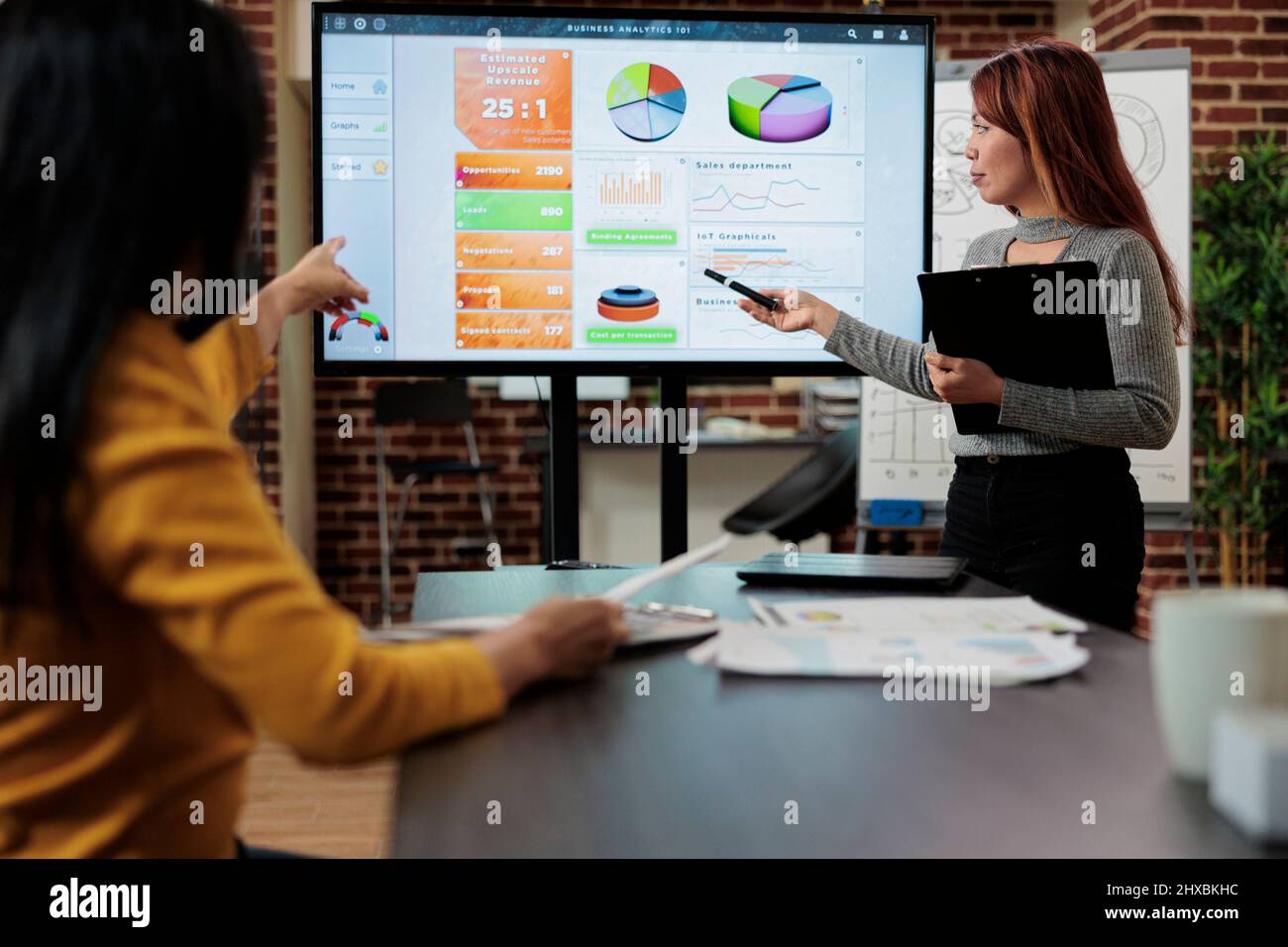 Imprenditore asiatico seduto accanto a monitor mostrando grafici di marketing brainstorming idee per il progetto di partnership. Il team di gestione discute della strategia aziendale che lavora in startup Office. Ambiente di lavoro moderno Foto Stock