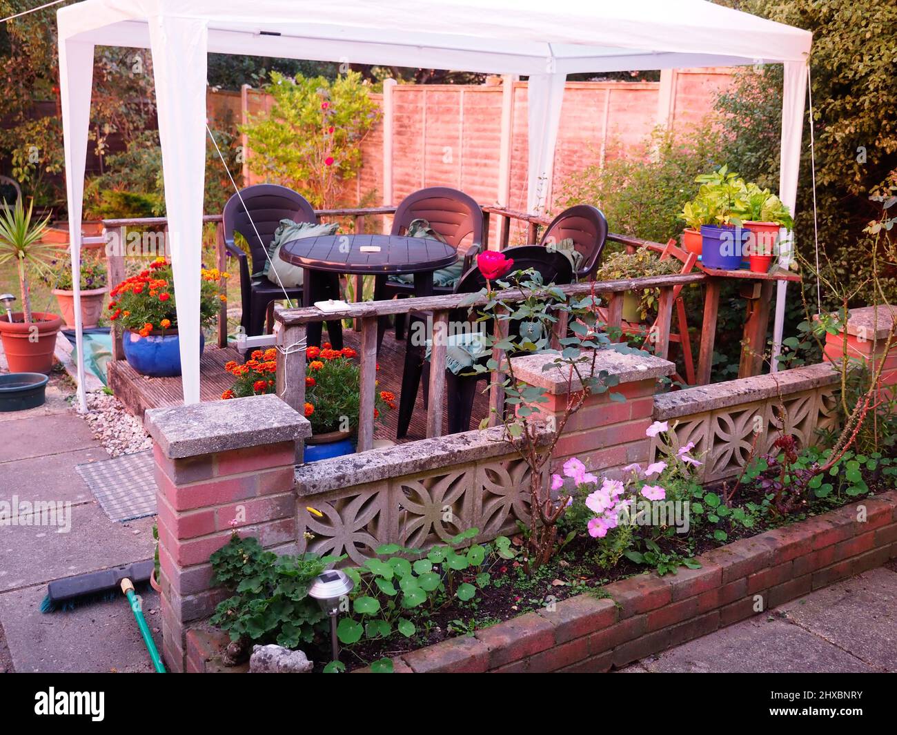Sedie da giardino in plastica e tavolo sotto un gazebo in plastica bianca su un piccolo pezzo di terrazze in legno Foto Stock