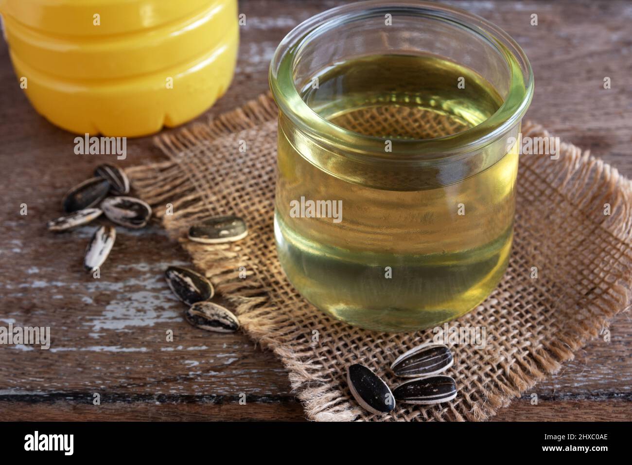 Olio di girasole in vetro trasparente su sfondo rustico Foto Stock