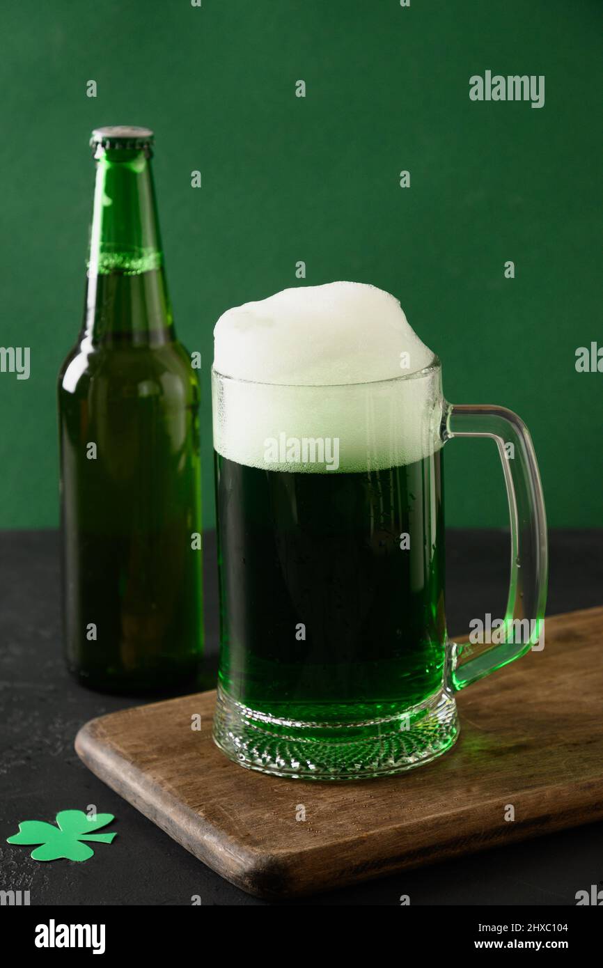 La tradizionale birra verde e bottiglia di Patrick su sfondo verde. Formato verticale. Primo piano. Foto Stock