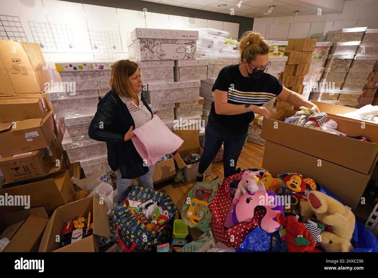 Jackie Crawford (a sinistra) e Amanda Findlay confezionano articoli in baby box preamati per inviare ai rifugiati in fuga dal conflitto in Ucraina, presso il centro commerciale Glasgow Forge di Parkhead, Glasgow. Data foto: Venerdì 11 marzo 2022. Foto Stock