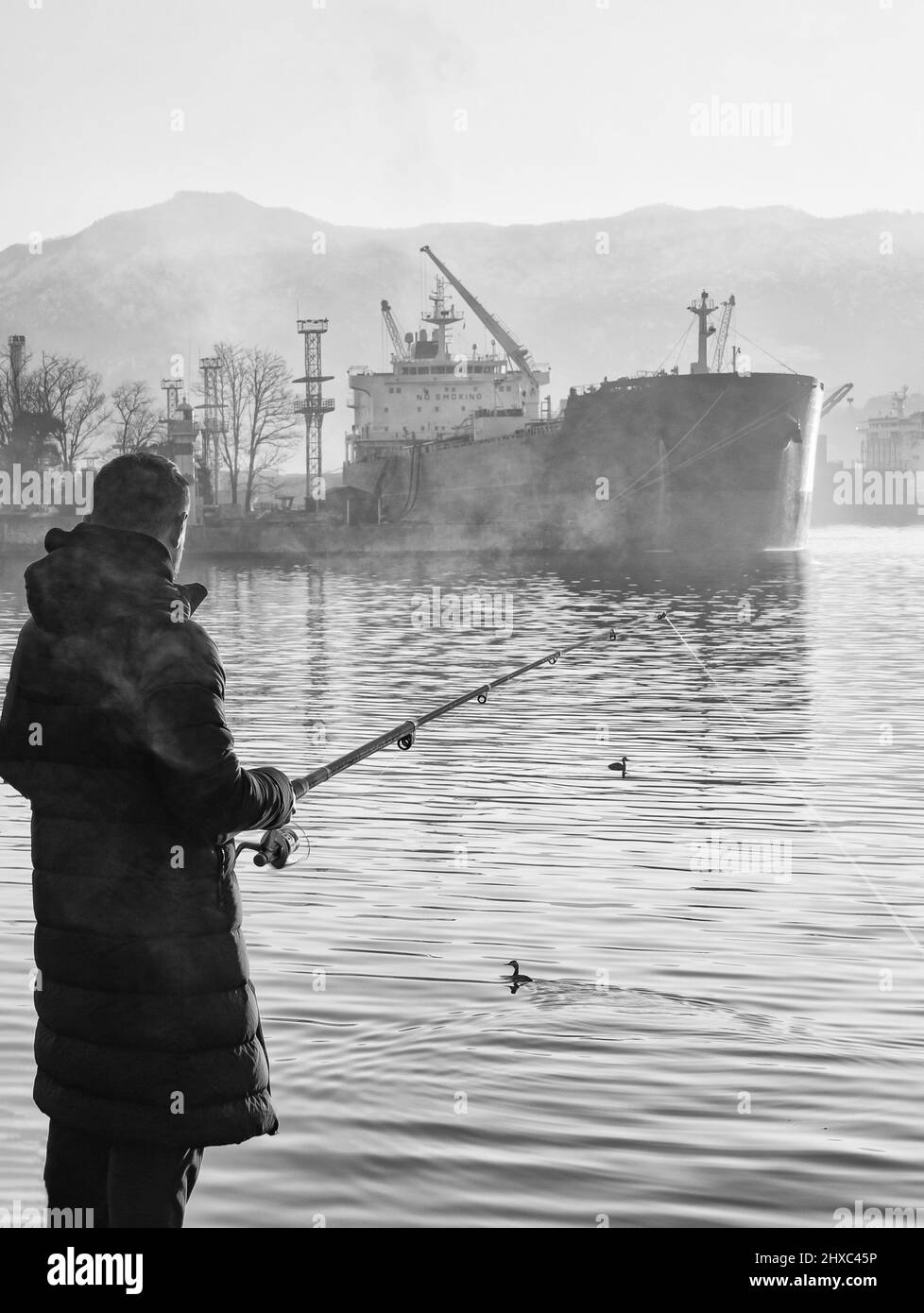 Pescatore sul terrapieno di mattina presto, quando la nebbia cadde Foto Stock
