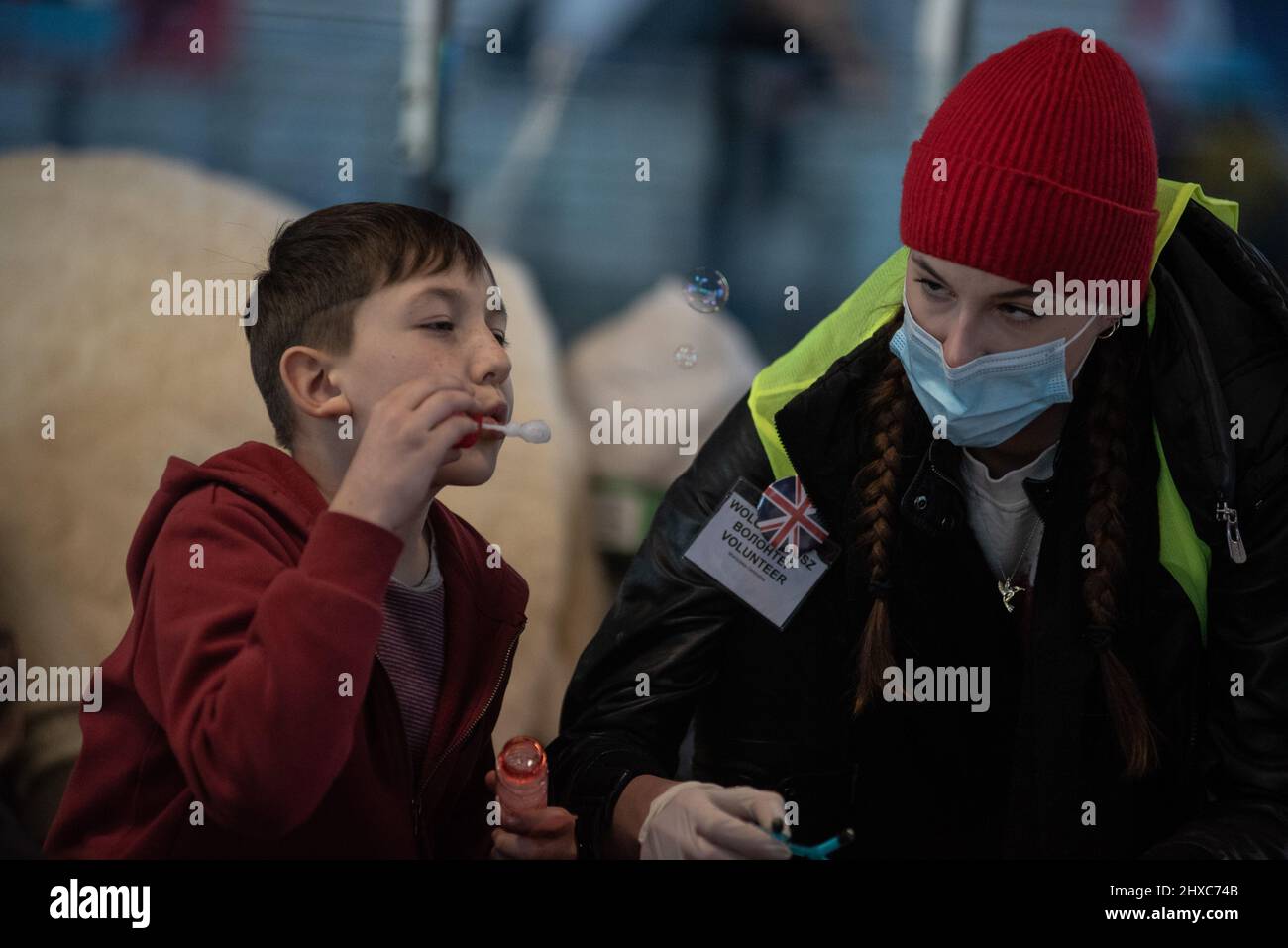 Varsavia, Polonia. 11th Mar 2022. 11 marzo 2022: I bambini rifugiati ucraini giocano in un vivaio realizzato da volontari all'interno delle strutture della stazione ferroviaria di Varsavia. Nella foto, un bambino gioca con bolle di sapone con un volontario (Credit Image: © Hector Adolfo Quintanar Perez/ZUMA Press Wire) Credit: ZUMA Press, Inc./Alamy Live News Foto Stock