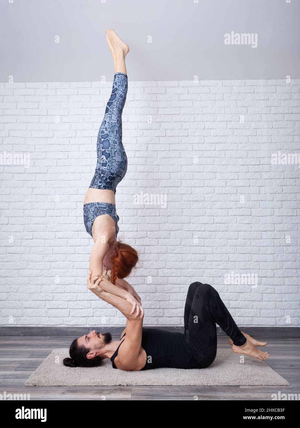 Giovane coppia che si diverte a casa con alcune pose acro yoga in luoghi diversi. Foto Stock