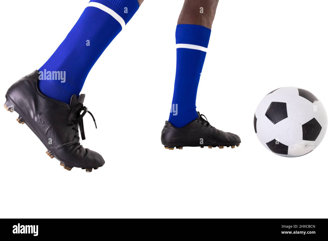 Sezione bassa del giovane giocatore afro-americano che calcia la palla di calcio su sfondo bianco Foto Stock