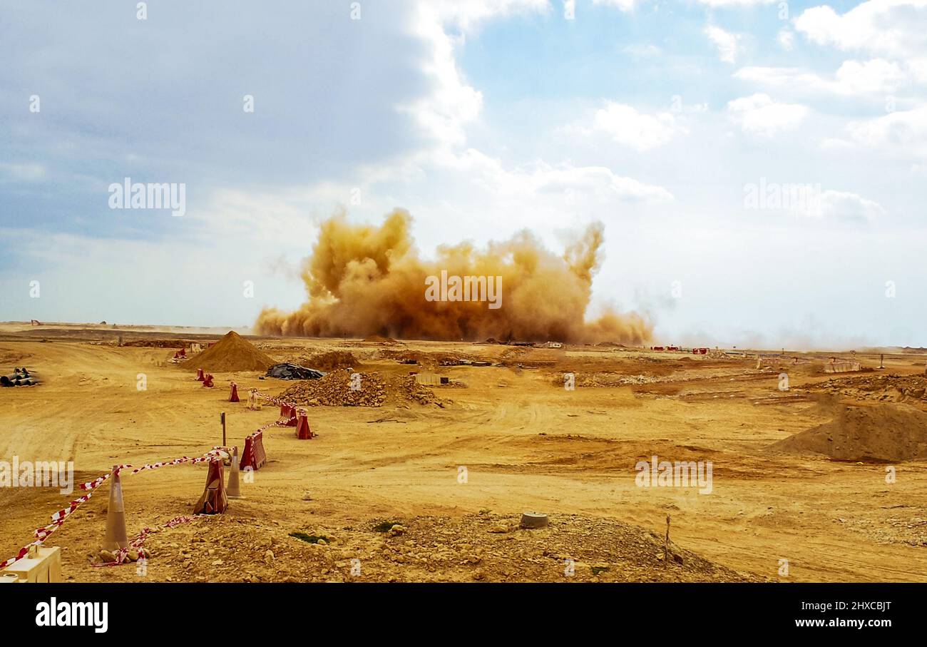 Detriti di roccia e nubi di polvere durante l'esplosione del detonatore nel cantiere Foto Stock