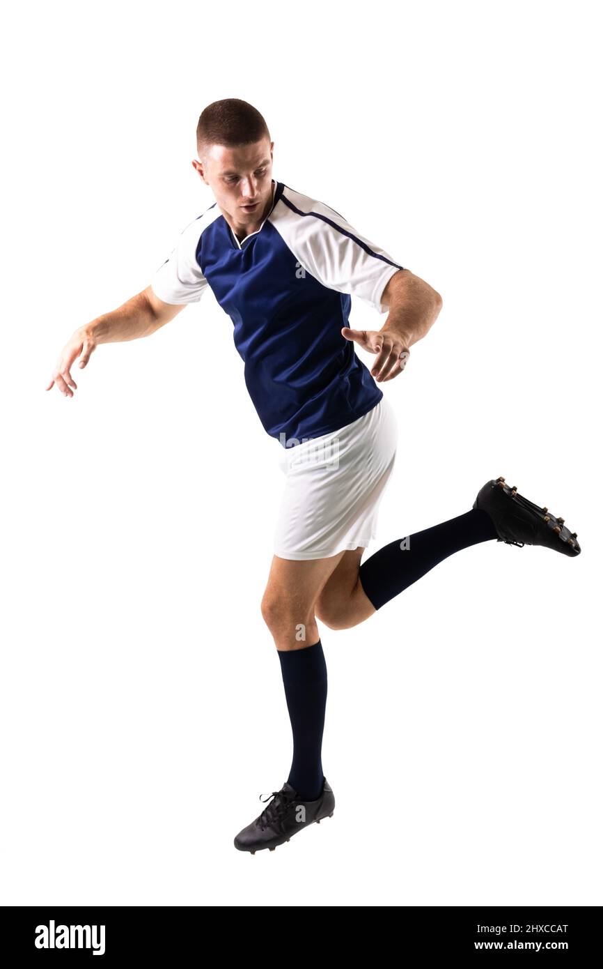 Intera lunghezza del giovane calciatore caucasico maschile in uniforme giocando su sfondo bianco Foto Stock