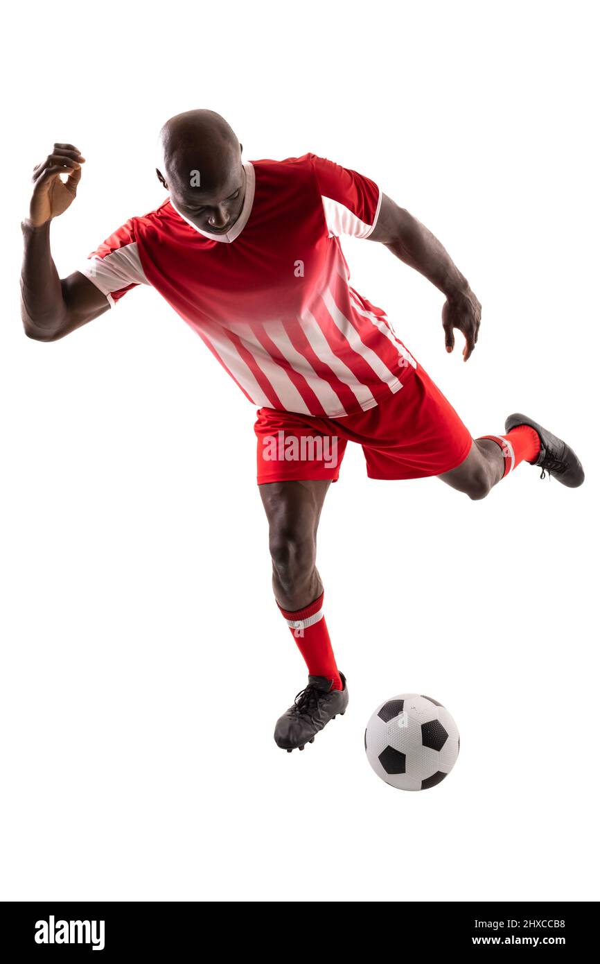 Tutta la lunghezza del giovane giocatore di calcio africano americano maschile calcia palla su sfondo bianco Foto Stock
