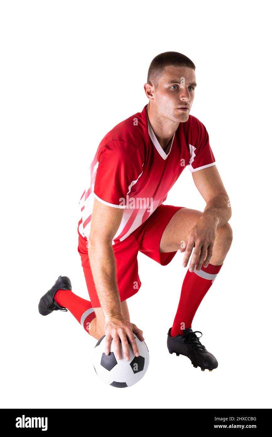 Tutta la lunghezza del giovane atleta caucasico maschio inginocchiato da pallone da calcio su sfondo bianco Foto Stock