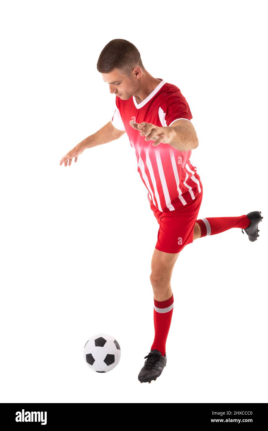 Tutta la lunghezza del giovane atleta caucasico maschio calci palla da calcio su sfondo bianco Foto Stock