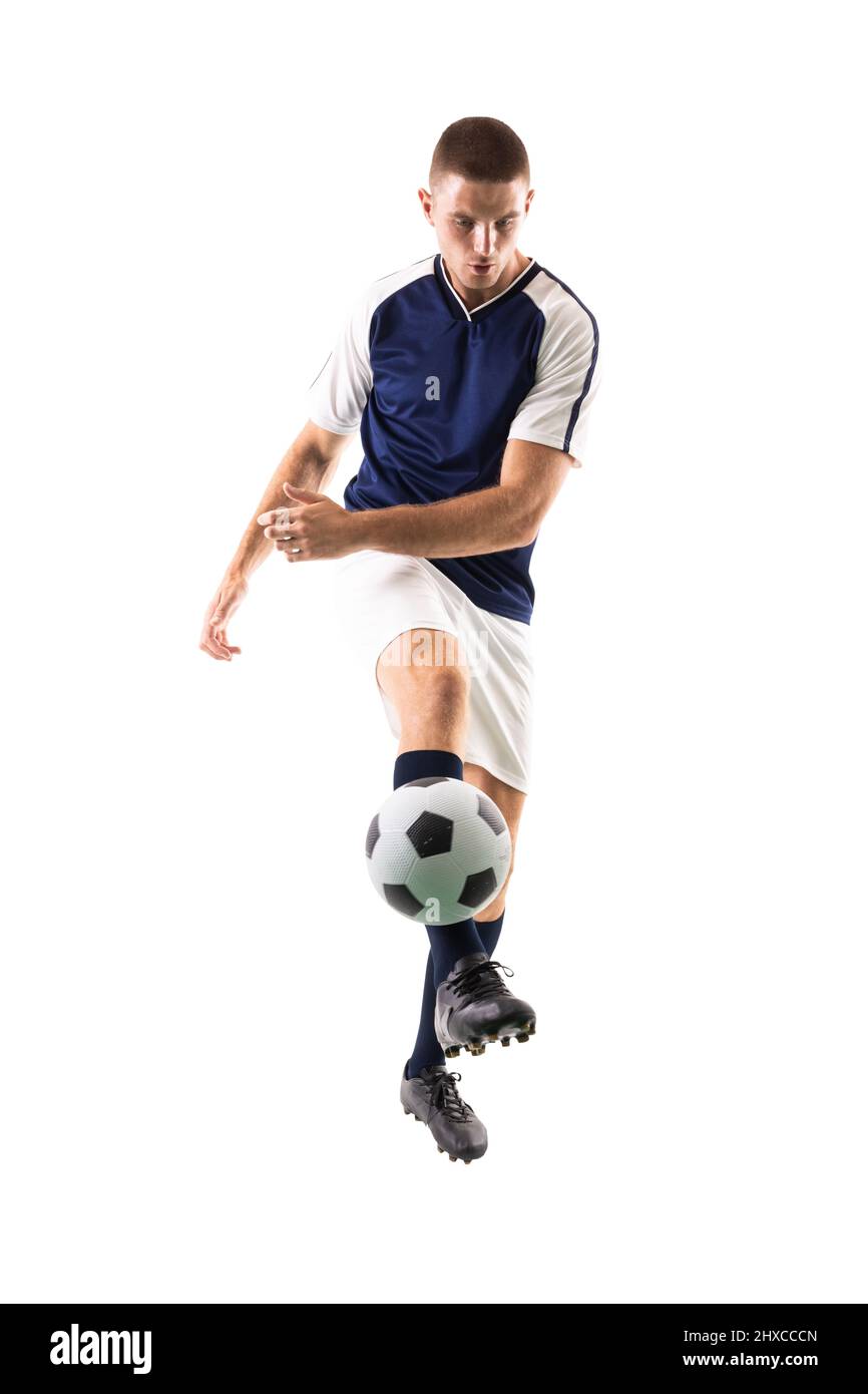 Tutta la lunghezza del giovane atleta caucasico maschio calci palla da calcio su sfondo bianco Foto Stock