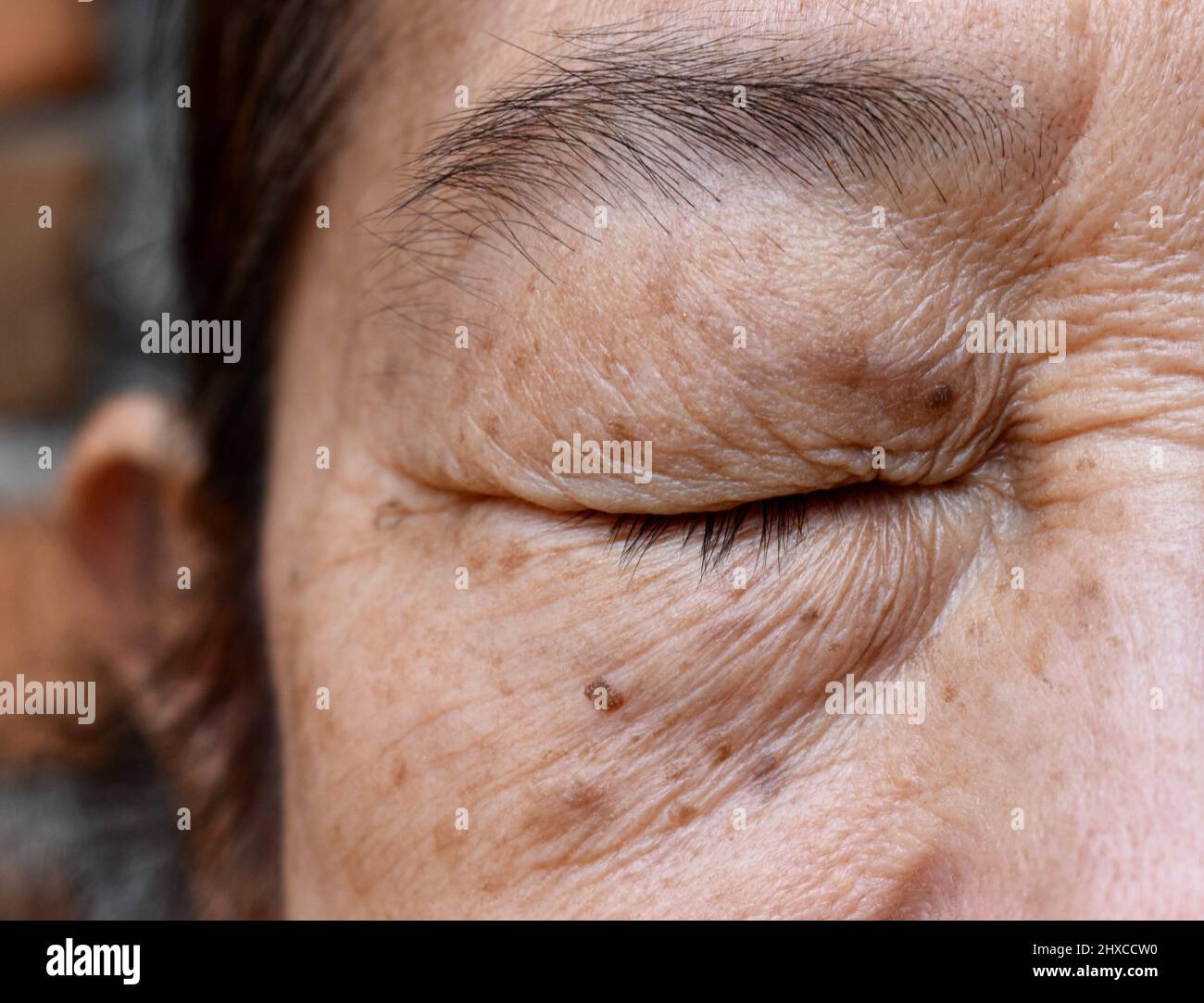 Rughe intorno ad occhio chiuso della donna anziana asiatica. Primo piano. Foto Stock
