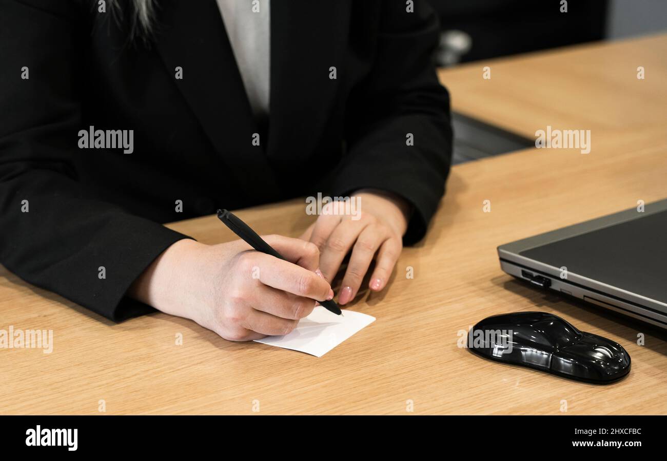 La donna sta scrivendo una nota nel suo ufficio. Foto Stock