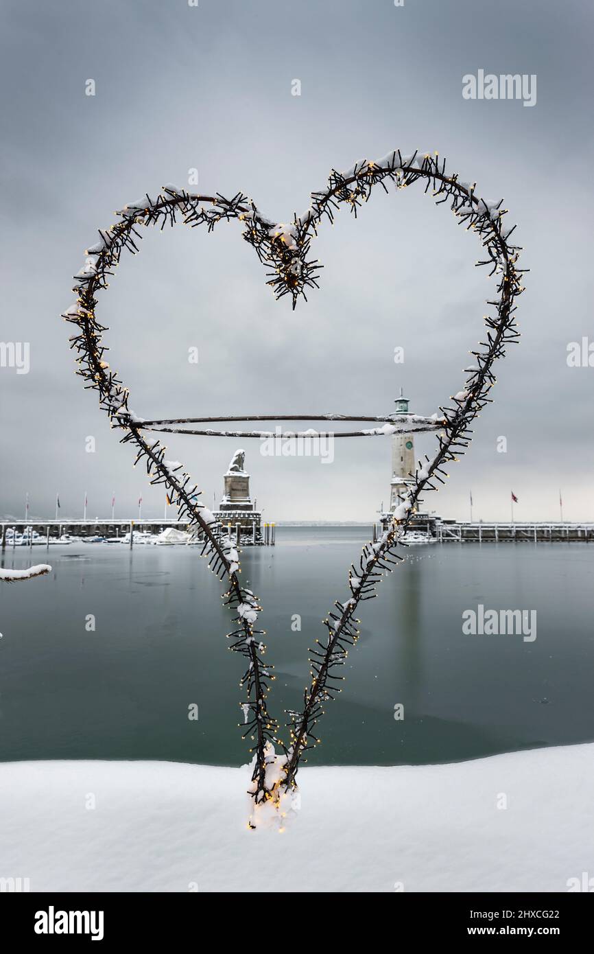 Cuore, serie di luci, ingresso del porto della città di Lindau sul lago di Costanza in inverno con neve Foto Stock