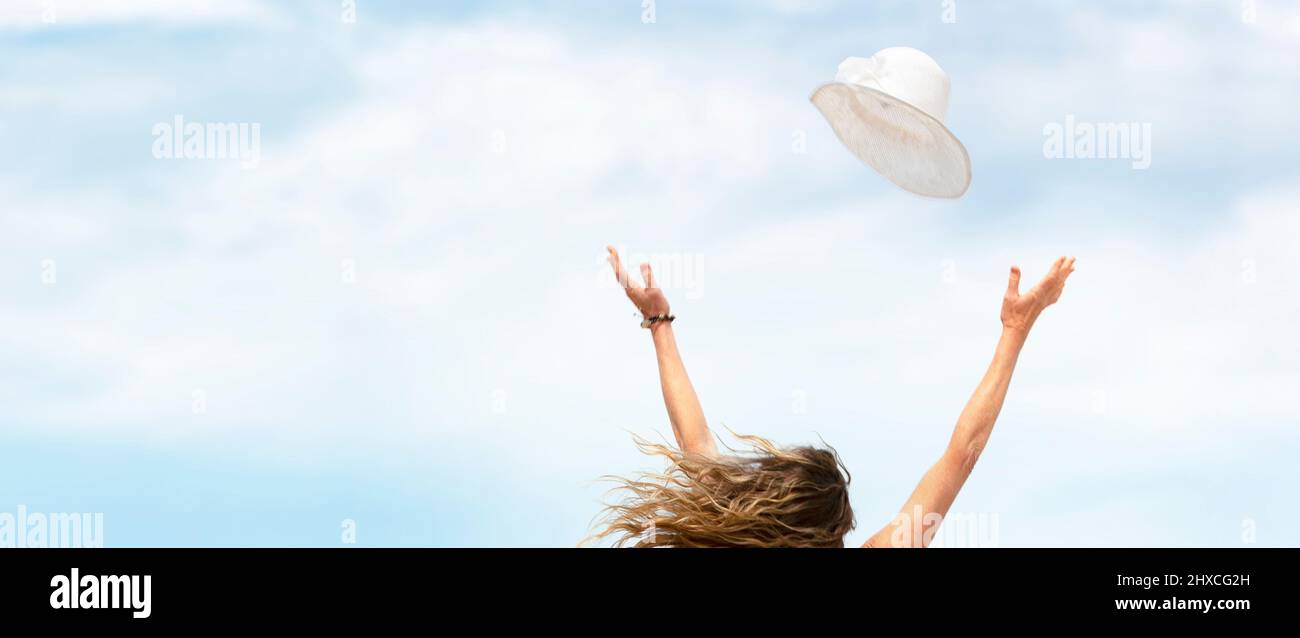 Cappello volante con braccia di donna distese di fronte al cielo Foto Stock