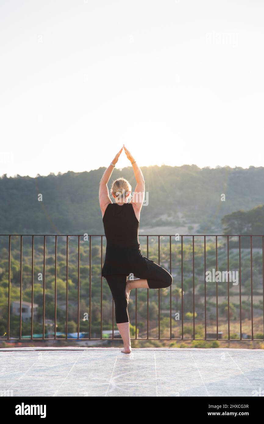 Donna che pratica yoga all'aperto con vista sulla valle Foto Stock