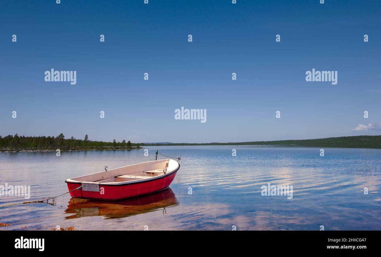 Barca a remi rossa sulla riva di un lago a Scandianvia Foto Stock