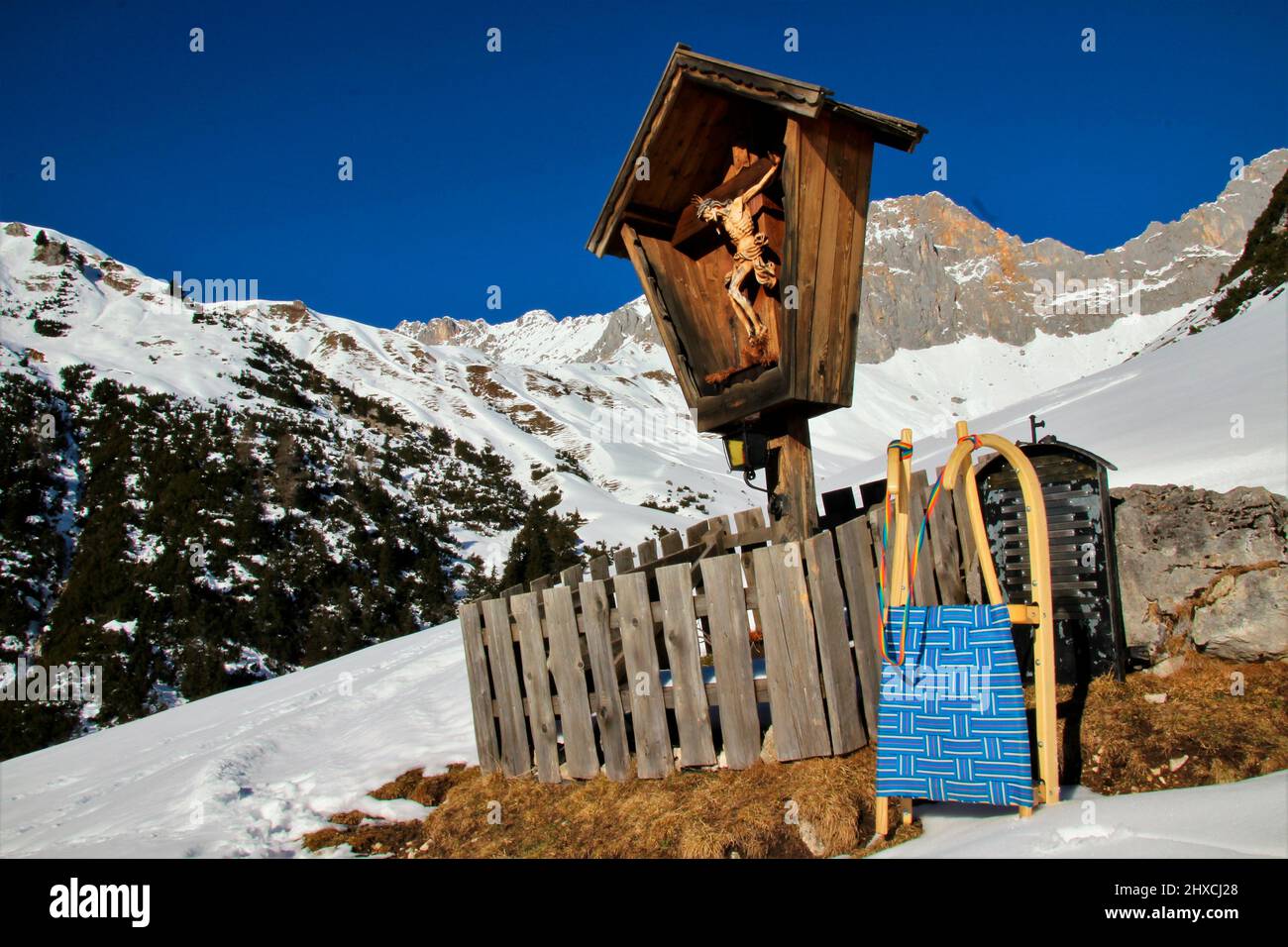 Escursione invernale al Wang Alm nel Gaistal, slitte di fronte a una croce di montagna, paesaggio di montagna nella neve, Austria, Tirolo, vacanza, inverno, tempo da sogno Foto Stock