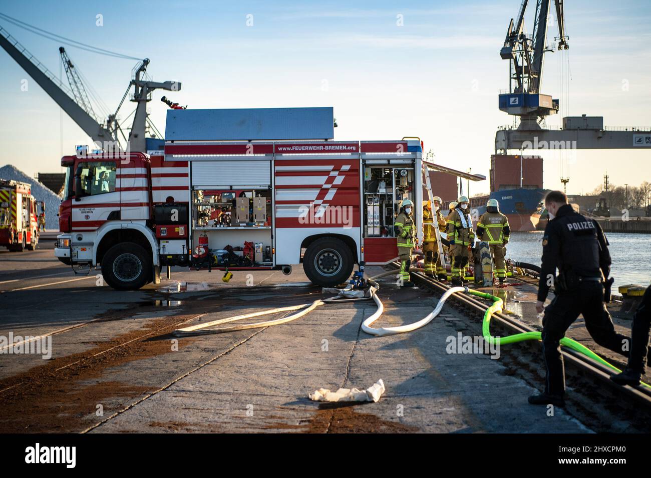 Brema, Germania. 11th Mar 2022. Le forze di emergenza del dipartimento dei vigili del fuoco e della polizia si trovano al porto. Un grande mucchio di torba catturato fuoco nei porti industriali. Ai residenti delle aree circostanti è stato chiesto di tenere le porte e le finestre chiuse. Il reparto antincendio era sulla scena con circa 80 addetti alle emergenze. Credit: Sina Schuldt/dpa/Alamy Live News Foto Stock