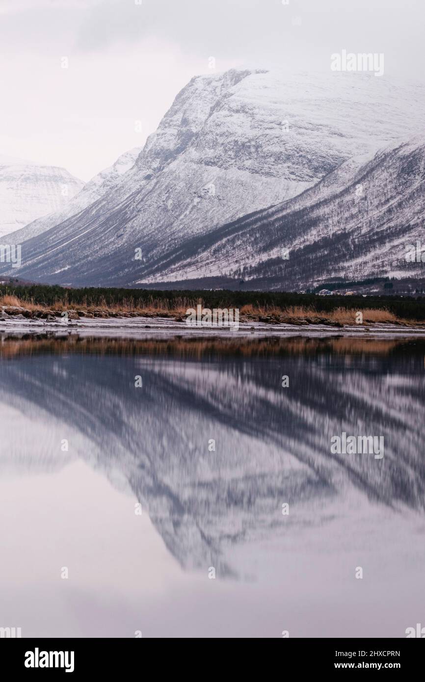 Montagna coperta di neve che si specchia nel lago fiordo in Norvegia Foto Stock