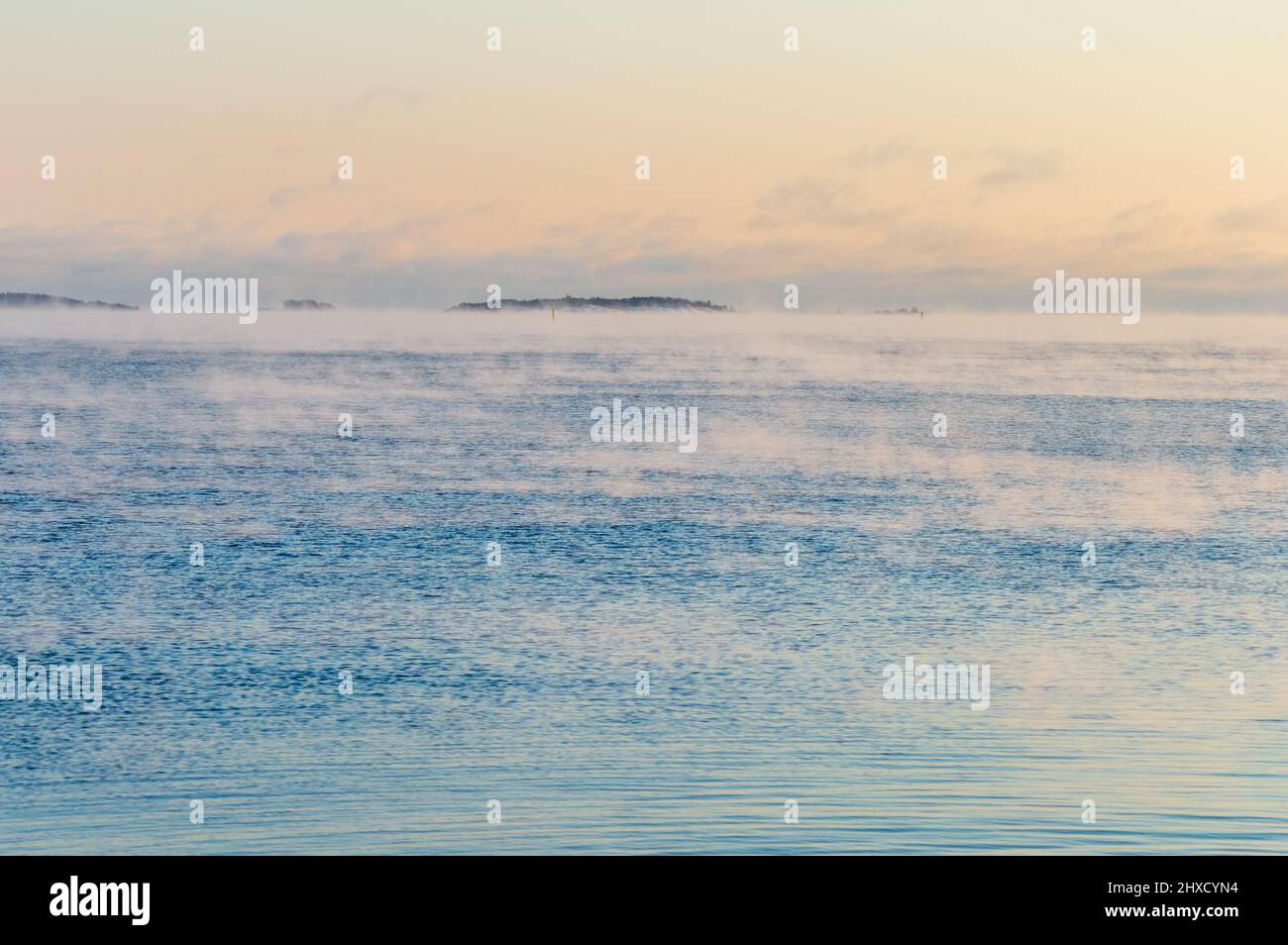 Vista minima del mare dalla costa di Helsinki. Il tempo è così freddo che l'acqua gela e gela una leggera nebbia sulla sua superficie Foto Stock