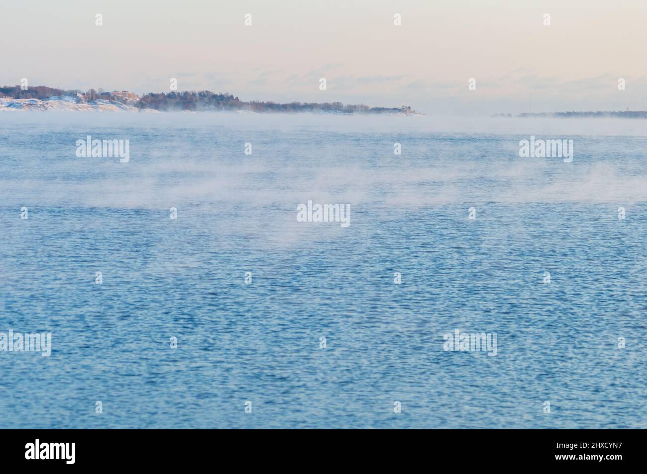 Vista minima del mare dalla costa di Helsinki. Il tempo è così freddo che l'acqua gela e gela una leggera nebbia sulla sua superficie Foto Stock