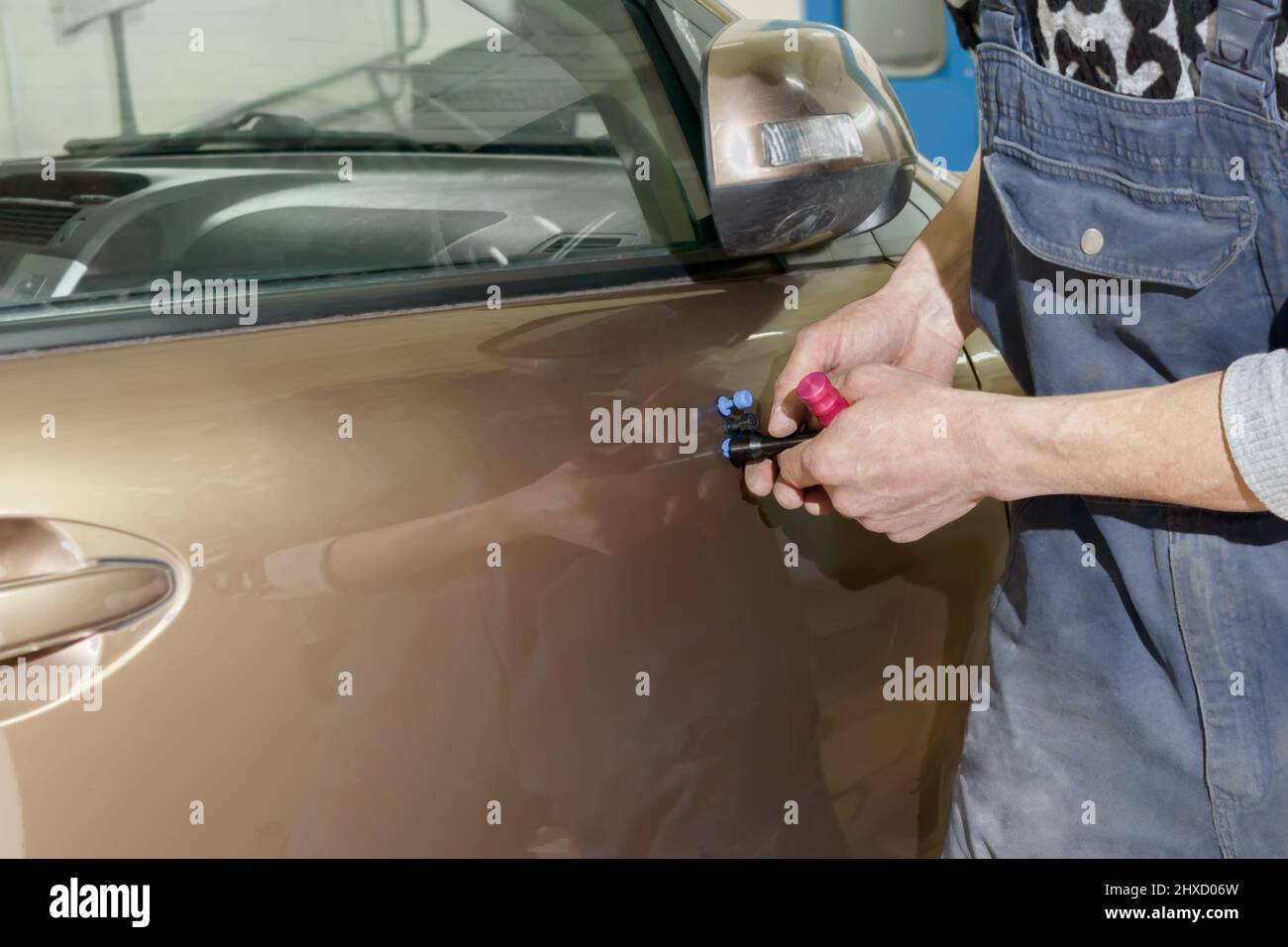 Le mani di un pittore professionista che ripara ammaccature senza pittura. Foto Stock