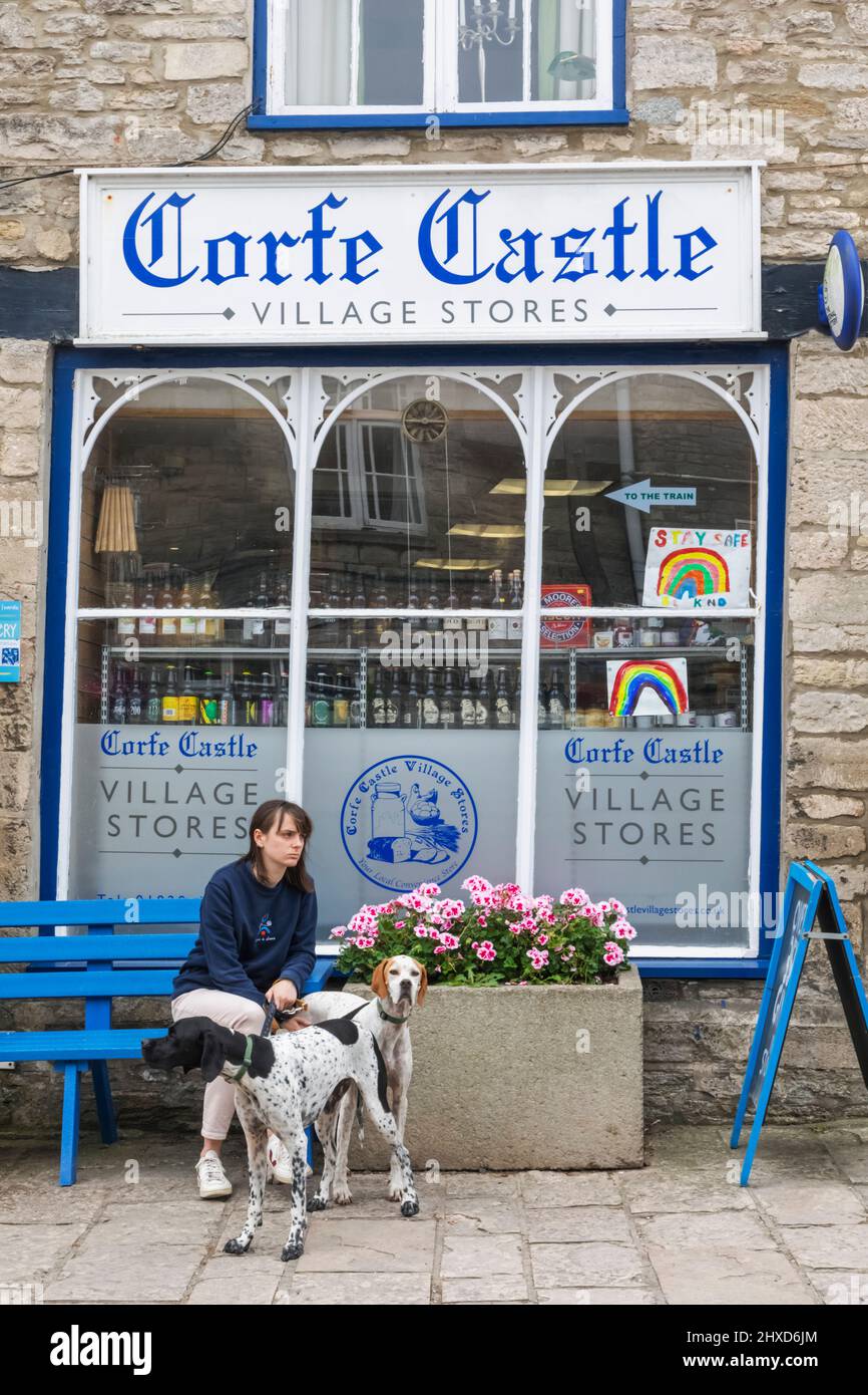 Inghilterra, Dorset, Isola di Purbeck, Corfe Castle Village, Donna e cani di fronte al Corfe Castle Village Stores Foto Stock