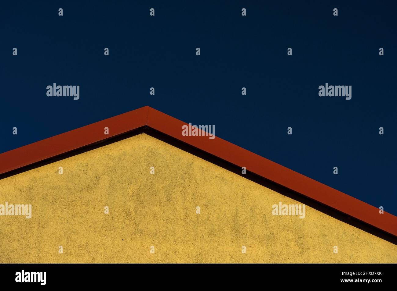 Parete gialla della casa con tetto rosso di fronte al cielo blu profondo, Vienna, Austria Foto Stock