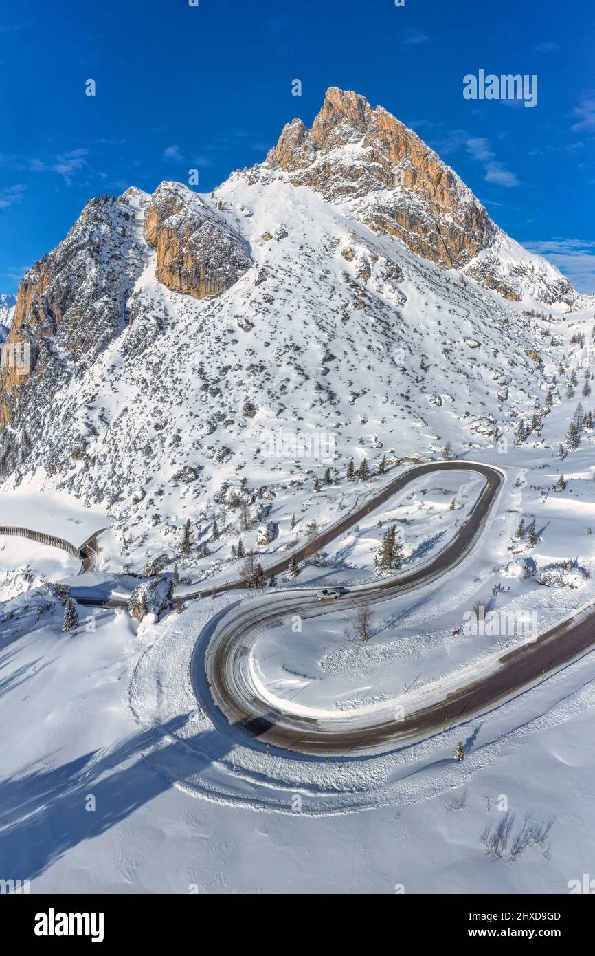 Europa, Italia, Veneto, provincia di Belluno, il tornante si snoda lungo la strada del Passo Falzarego in inverno, sullo sfondo il Sass de Stria, Dolomiti Foto Stock